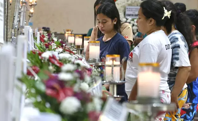 Relatives and friends stand near coffins in Bacayan, Cebu province, Philippines on Friday Nov. 7, 2025 after Typhoon Kalmaegi devastated the province and claimed lives. (AP Photo/Jacqueline Hernandez)