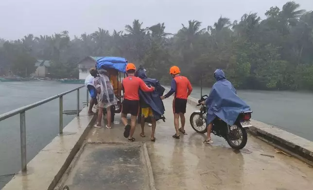 In this photo provided by the Philippine Coast Guard, rescuers evacuate people to safer grounds in Quezon province, eastern Philippines as Typhoon Fung-wong enters the country on Sunday Nov. 9 2025. (Philippine Coast Guard via AP)