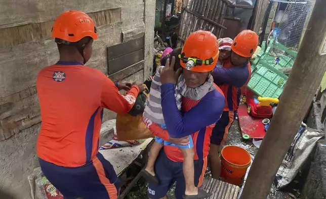 In this photo provided by the Philippine Coast Guard, rescuers evacuate residents to safer grounds Laurel, Batangas province, Philippines as Typhoon Fung-wong affects the country, Sunday Nov. 9 2025. (Philippine Coast Guard via AP)