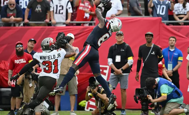 New England Patriots wide receiver Stefon Diggs (8) catches a pass for a touchdown against Tampa Bay Buccaneers safety Antoine Winfield Jr. (31) during the first half of an NFL football game Sunday, Nov. 9, 2025, in Tampa, Fla. (AP Photo/Jason Behnken)