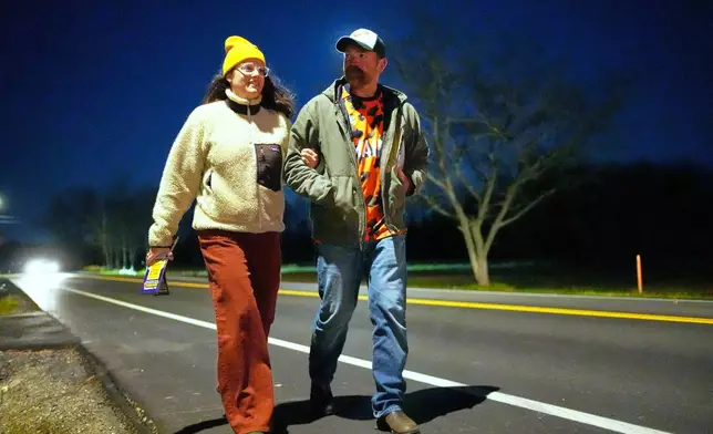 Graham Platner, Democratic candidate for U.S. Senate, and his wife, Amy Gertner, walk on the shoulder of the road while canvassing for a citizen's initiate on Election Day, Tuesday, Nov. 4, 2025, in Ellsworth, Maine. (AP Photo/Robert F. Bukaty)