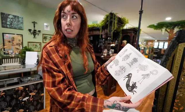 Tattoo artist Mischa Ostberg shows a visitor a selection of Anglo-Celtic patterns, Nov. 3, 2025, in Ellsworth, Maine. (AP Photo/Robert F. Bukaty)