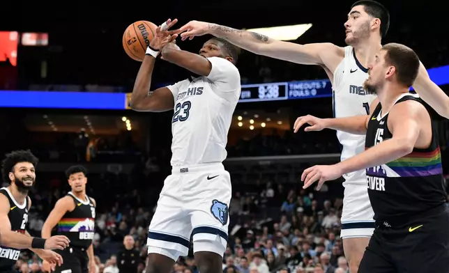 Memphis Grizzlies forward Cedric Coward (23) center Zach Edey, second from right, and Denver Nuggets center Nikola Jokic reach for the ball in the first half of an NBA basketball game, Monday, Nov. 24, 2025, in Memphis, Tenn. (AP Photo/Brandon Dill)
