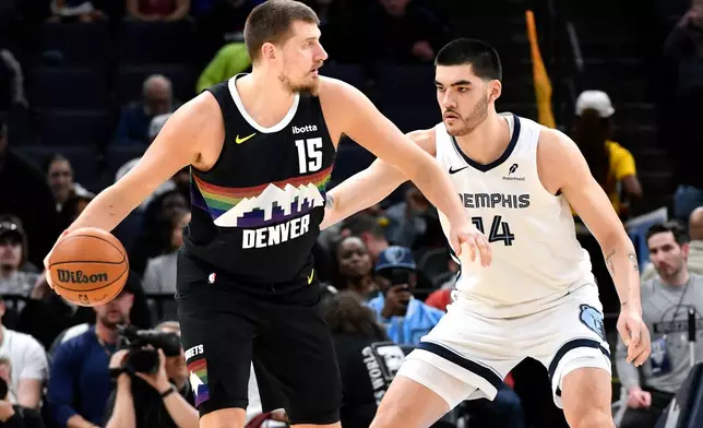 Denver Nuggets center Nikola Jokic (15) handles the ball against Memphis Grizzlies center Zach Edey in the first half of an NBA basketball game, Monday, Nov. 24, 2025, in Memphis, Tenn. (AP Photo/Brandon Dill)