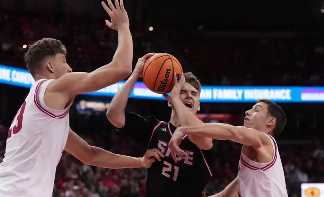 SIUE's Myles Thompson is fouled driving between Wisconsin's Will Garlock and Aleksas Bieliauskas during the first half of an NCAA college basketball game Monday, Nov. 17, 2025, in Madison, Wis. (AP Photo/Morry Gash)