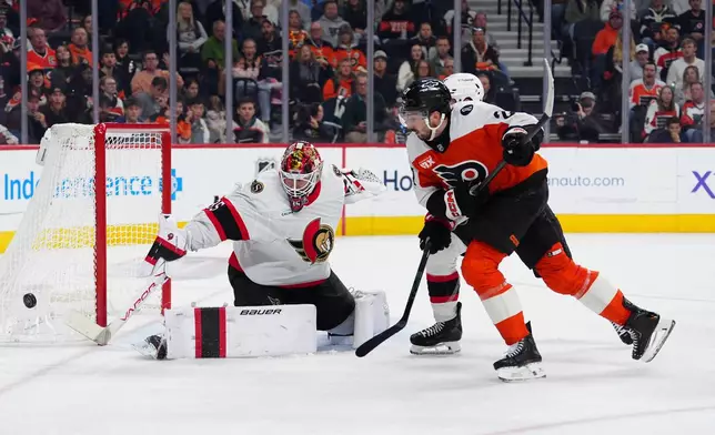 Ottawa Senators goaltender Linus Ullmark, left, makes a save as Jake Sanderson, rear and Philadelphia Flyers' Noah Cates (27) race for the puck during the second period of an NHL hockey game, Saturday, Nov. 8, 2025, in Philadelphia. (AP Photo/Derik Hamilton)