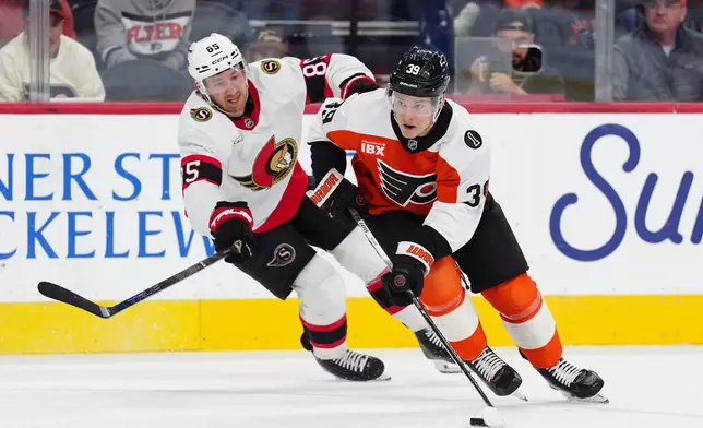 Philadelphia Flyers' Matvei Michkov, right, skates the puck past Ottawa Senators' Jake Sanderson during the second period of an NHL hockey game, Saturday, Nov. 8, 2025, in Philadelphia. (AP Photo/Derik Hamilton)