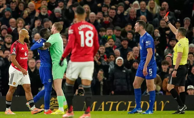 Everton's Idrissa Gueye, second left, is held back by teammate Jordan Pickford as he argues with Michael Keane after getting a red card from referee Tony Harrington during the English Premier League soccer match between Manchester United and Everton in Manchester, England, Monday, Nov. 24, 2025. (AP Photo/Dave Thompson)