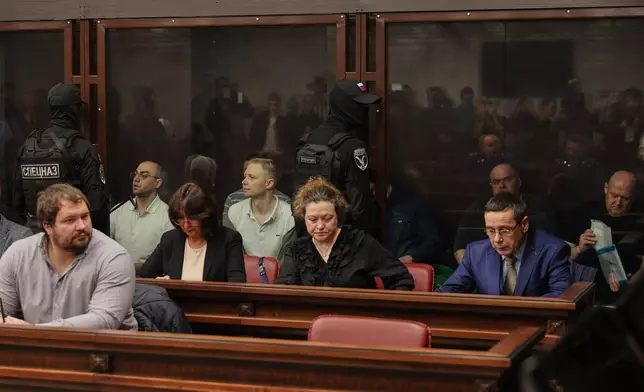 Eight men tried on terrorism charges over a 2022 attack on the bridge linking Russia to Moscow-annexed Crimea stand in a glass cage in a military court in Rostov-on-Don, Russia, on Thursday, Nov. 27, 2025. (AP Photo)