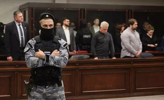 People tried on terrorism charges over a 2022 attack on the bridge linking Russia to Moscow-annexed Crimea stand in a glass cage, back, in a military court in Rostov-on-Don, Russia, on Thursday, Nov. 27, 2025. (AP Photo)