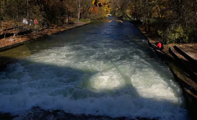 A man films at the Eisbach, where the famous wave usually forms, in Munich, Germany, Wednesday, Nov. 5, 2025. (AP Photo/Matthias Schrader)