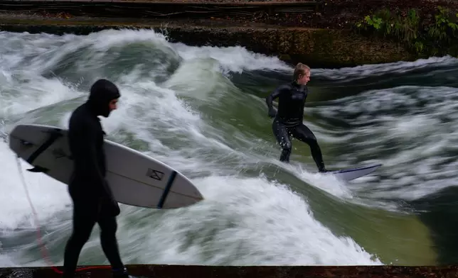 FILE - Surfer ride on an artificial wave in the river 'Eisbach' at the 'Englischer Garten' (English Garden) downtown in Munich, Germany, Monday, Oct. 6, 2025. (AP Photo/Matthias Schrader, File)