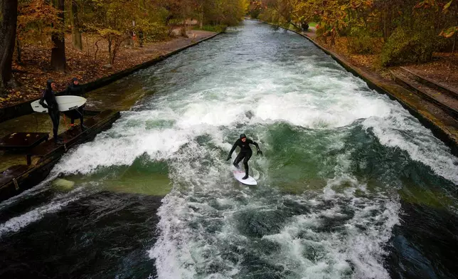 FILE - A surfer rides on an artificial wave in the river 'Eisbach' at the 'Englischer Garten' (English Garden) downtown in Munich, Germany, Monday, Nov. 11, 2024. (AP Photo/Matthias Schrader, File)