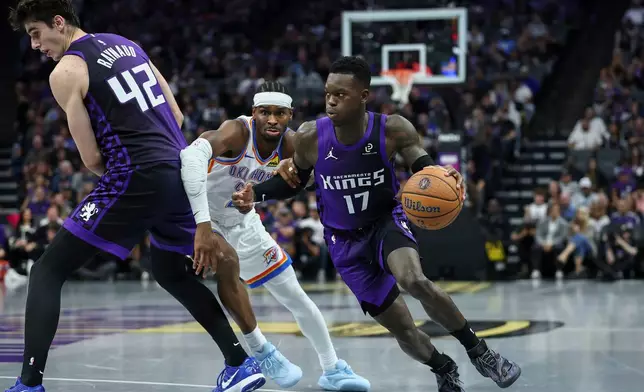 Sacramento Kings guard Dennis Schröder (17) drives to the basket as Sacramento center Maxime Raynaud (42) screens Oklahoma City Thunder guard Shai Gilgeous-Alexander, center, during the first half of an NBA Cup basketball game Friday, Nov. 7, 2025, in Sacramento, Calif. (AP Photo/Sara Nevis)