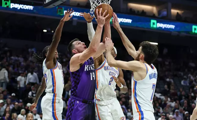 Sacramento Kings forward Drew Eubanks (19) makes a reverse layup surrounded by Oklahoma City Thunder defenders during the first half of an NBA Cup basketball game Friday, Nov. 7, 2025, in Sacramento, Calif. (AP Photo/Sara Nevis)