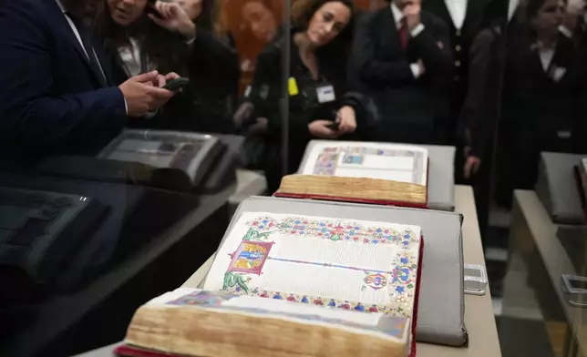 Reporters look at the 15th century Borso D'Este Bible, comprising two illuminated manuscripts, after its unveiling at the Italian Senate as part of the Vatican's Holy Year celebrations in Rome, Thursday, Nov. 13, 2025. (AP Photo/Alessandra Tarantino)