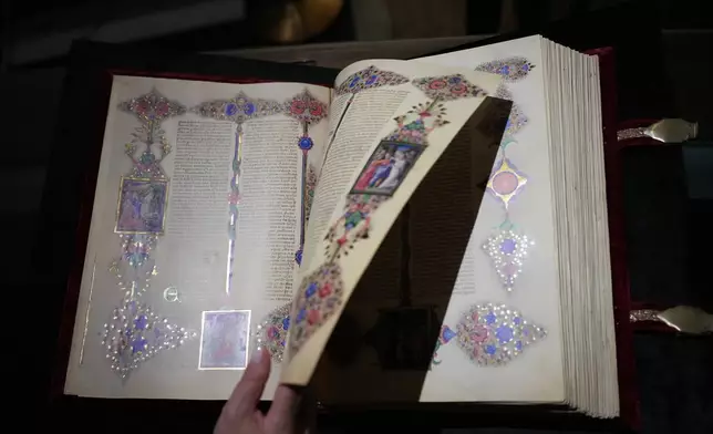 A journalist flips through a faithful reproduction of the 15th century Borso D'Este Bible, comprising two illuminated manuscripts, during its unveiling at the Italian Senate as part of the Vatican's Holy Year celebrations in Rome, Thursday, Nov. 13, 2025. (AP Photo/Alessandra Tarantino)