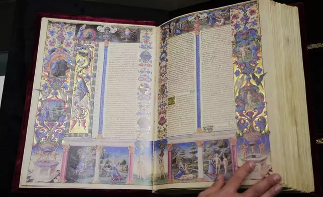 A journalist flips through a faithful reproduction of the 15th century Borso D'Este Bible, comprising two illuminated manuscripts, during its unveiling at the Italian Senate as part of the Vatican's Holy Year celebrations in Rome, Thursday, Nov. 13, 2025. (AP Photo/Alessandra Tarantino)