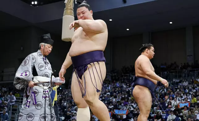 Sumo wrestler Yoshinofuji, center, reacts after being beaten by Yokozuna Hoshoryu during their bout at the Kyushu Grand Sumo Tournament in Fukuoka, southern Japan on Nov. 17, 2025. (Kotaro Ueda/Kyodo News via AP)