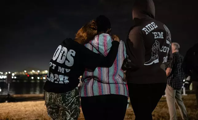 Community members embrace during a vigil for those killed and missing after a UPS plane crashed, at the Great Lawn, Friday, Nov. 7, 2025, in Louisville, Ky. (AP Photo/Jon Cherry)