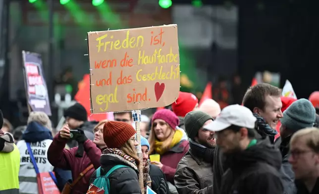 A demonstrator holds up a sign that reads: "Peace is when skin color and gender don't matter", as thousands gather in Giessen, Germany, Saturday Nov. 29, 2025, as the far-right Alternative for Germany’s new youth organization is set to kick off its founding convention. (Michael Brandt/dpa via AP)