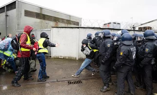 Police officers stand near the assembly hall and block demonstrators' access during a protest against the founding of a new AfD youth organization, in Hesse, Germany, Saturday, Nov. 29, 2025. (Boris Roessler/dpa via AP)