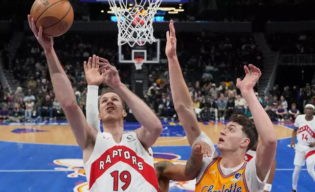 Toronto Raptors center Jakob Poeltl shoots over Charlotte Hornets center Ryan Kalkbrenner during the first half of an NBA basketball game, Saturday, Nov. 29, 2025, in Charlotte, N.C. (AP Photo/Chris Carlson)