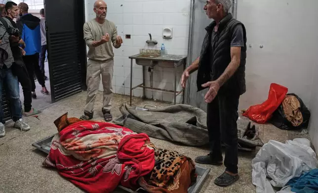 Palestinians check the bodies of people killed in Israeli strikes on the Gaza Strip at the morgue of Al-Aqsa Hospital in Deir al-Balah, Saturday, Nov. 22, 2025. (AP Photo/Abdel Kareem Hana)