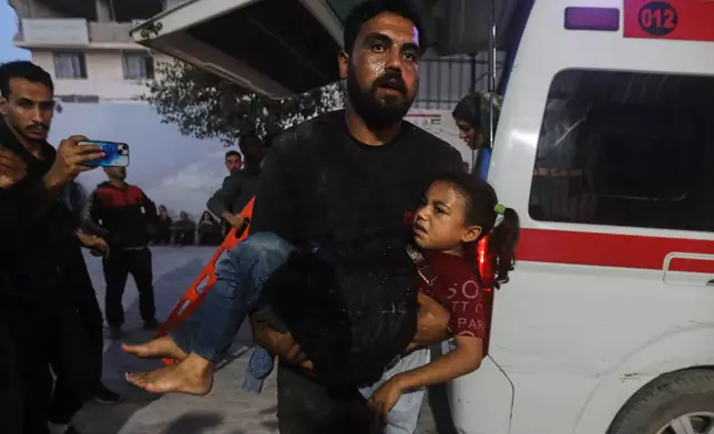 A Palestinian man carries a wounded girl into al-Shifa Hospital following Israeli strikes on the Gaza Strip, Saturday, Nov. 22, 2025. (AP Photo/Yousef Al Zanoun)