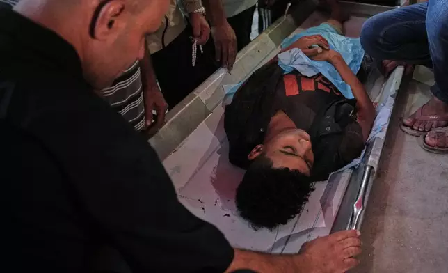 Relatives mourn over the body of a Palestinian killed in Israeli strikes on the Gaza Strip at Al-Aqsa Hospital in Deir al-Balah, Saturday, Nov. 22, 2025. (AP Photo/Abdel Kareem Hana)