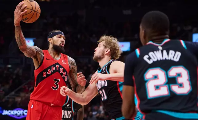 Toronto Raptors' Brandon Ingram (3) drives to the net past Memphis Grizzlies' Jock Landale (31) and Cedric Coward (23) during first-half NBA basketball game action in Toronto, Sunday, Nov. 2, 2025. (Sammy Kogan/The Canadian Press via AP)