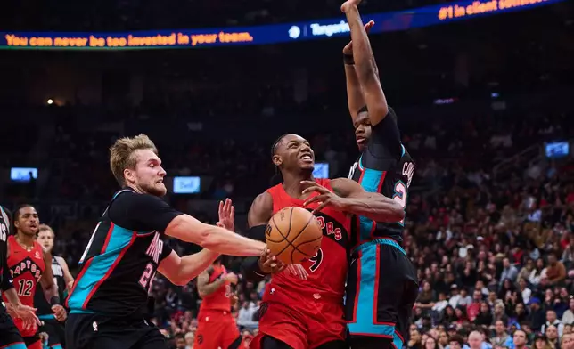 Toronto Raptors' RJ Barrett (9) drives between Memphis Grizzlies' Cam Spencer, front left, and Cedric Coward, right, during first-half NBA basketball game action in Toronto, Sunday, Nov. 2, 2025. (Sammy Kogan/The Canadian Press via AP)