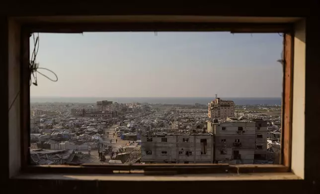Displaced Palestinians walk through a makeshift tent camp in the Muwasi area of Khan Younis, in the Gaza Strip, Saturday, Nov. 8,2025. (AP Photo/Abdel Kareem Hana)