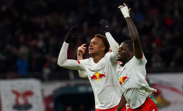 Leipzig's scorer Assan Ouedraogo, left, and Castello Lukeba, right, celebrate the opening goal during the German Bundesliga Soccer match between RB Leipzig and Werder Bremen in Leipzig, Germany, Sunday, Nov. 23, 2025. (Jan Woitas/dpa via AP)