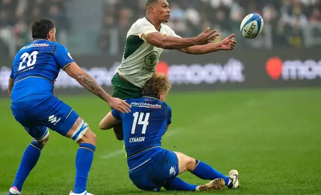South Africa's Damian Willemse passes as Italy's Louis Lynagh makes a tackle during the rugby union Nations Series match between Italy and South Africa, in Turin, Italy, Saturday, Nov. 15, 2025. (AP Photo/Luca Bruno)