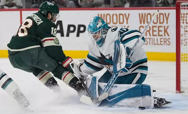 San Jose Sharks goaltender Yaroslav Askarov (30) blocks a shot by Minnesota Wild center Vinnie Hinostroza (18) during the first period of an NHL hockey game, Tuesday, Nov. 11, 2025, in St. Paul, Minn. (AP Photo/Abbie Parr)