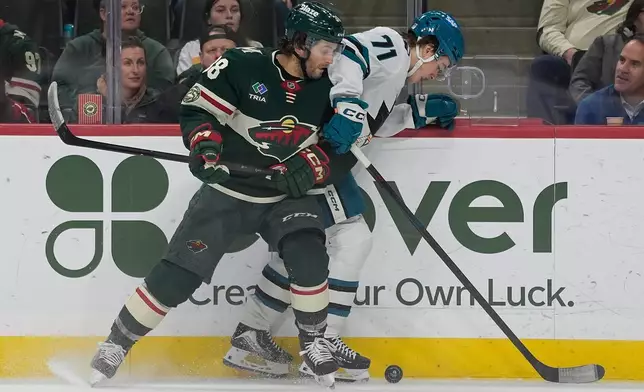 Minnesota Wild right wing Ryan Hartman (38) and San Jose Sharks center Macklin Celebrini (71) battle for the puck during the first period of an NHL hockey game, Tuesday, Nov. 11, 2025, in St. Paul, Minn. (AP Photo/Abbie Parr)