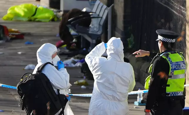 Forensic investigators look at the area where travellers left their belongings after a mass stabbing on a London-bound train in Huntingdon, England, Sunday, Nov. 2, 2025.(AP Photo/Kirsty Wigglesworth)