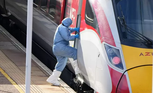 A forensic investigator enters the train after a mass stabbing on a London-bound train in Huntingdon, England, Sunday, Nov. 2, 2025.(AP Photo/Kirsty Wigglesworth)