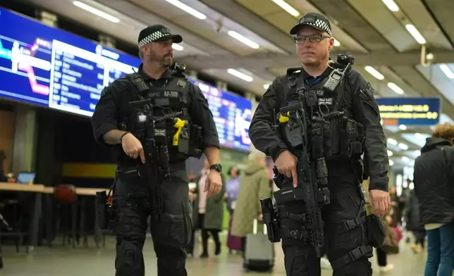 Armed police officers patrol the St Pancras International train station, in London, England, Monday, Nov. 3, 2025. (AP Photo/Kin Cheung)