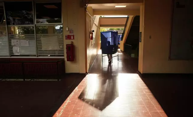 A worker carries away a voting booth after polls closed during general elections in Santiago, Chile, Sunday, Nov. 16, 2025. (AP Photo/Esteban Felix)