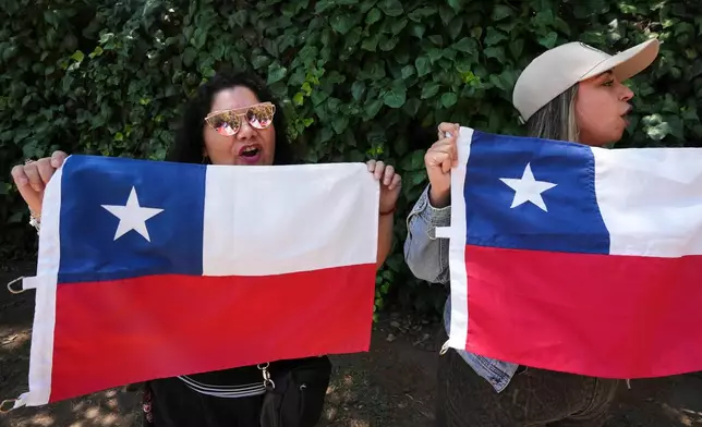 Supporters of presidential candidate Jeannette Jara of the Unidad por Chile coalition hold up Chilean flags outside the polling station before her arrival during general elections in Santiago, Chile, Sunday, Nov. 16, 2025. (AP Photo/Natacha Pisarenko)