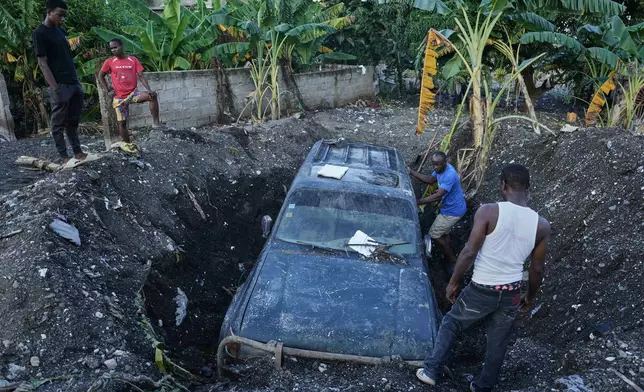 Residents work to remove a partially buried vehicle in the aftermath of Hurricane Melissa in Petit-Goave, Haiti, Thursday, Nov. 6, 2025. (AP Photo/Odelyn Joseph)