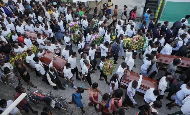 Mourners carry to the cemetery the coffins during the funeral of people killed by a landslide triggered by Hurricane Melissa in Petit Goave, Haiti, Saturday, Nov. 15, 2025. (AP Photo/Odelyn Joseph).