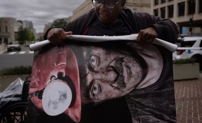 Roosevelt Neal, with the Fayette County Black Lung Association in W.Va., rolls up a banner of a coal miner who died of black lung disease, during a protest outside the U.S. Department of Labor, Oct. 14, 2025, in Washington. (AP Photo/Carolyn Kaster)