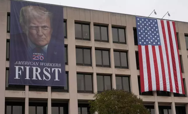 A banner with an image of President Donald Trump hangs outside the U.S. Department of Labor, Oct. 14, 2025, in Washington. (AP Photo/Carolyn Kaster)