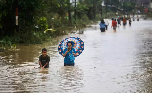 People wade through the water at a flooded street in Medan, North Sumatra, Indonesia, Thursday, Nov. 27, 2025. (AP Photo/Binsar Bakkara)