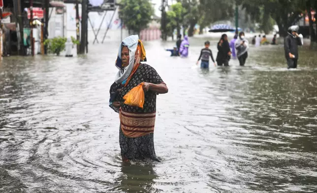 People wade through the water at a flooded street in Medan, North Sumatra, Indonesia, Thursday, Nov. 27, 2025. (AP Photo/Binsar Bakkara)