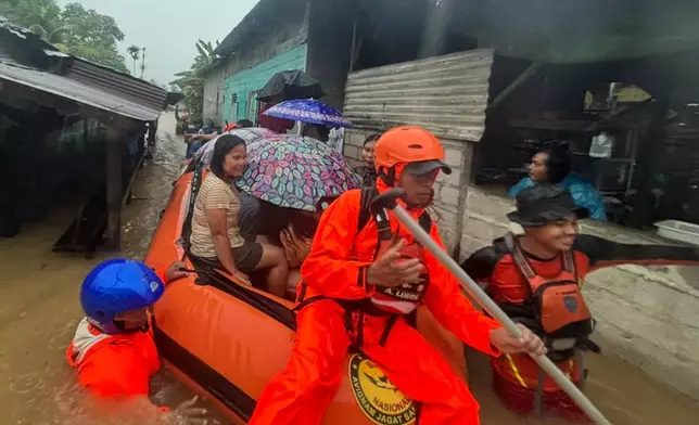 In this photo released by the Indonesian National Search and Rescue Agency (BASARNAS), rescuers on a rubber boat evacuate residents from their flooded home in North Sumatra province, Indonesia Tuesday, Nov. 25, 2025. (BASARNAS via AP)