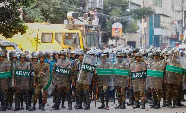 Army soldiers in riot gear stand guard as protesters shout slogans outside the demolished residence of Sheikh Mujibur Rahman, Bangladesh's former leader and the father of the country's ousted Prime Minister Sheikh Hasina following the verdict against her, in Dhaka, Bangladesh, Monday, Nov. 17, 2025. (AP Photo/ Rajib Dhar)